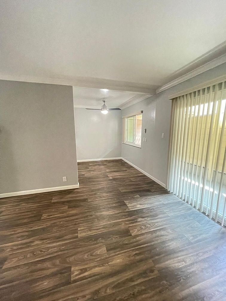 A room with wooden flooring and a window with curtains.