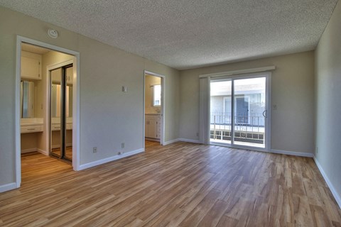 an empty living room with wood flooring and sliding glass doors