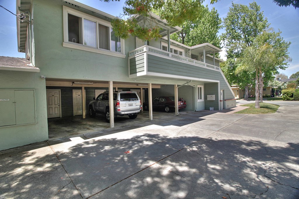 a green house with a parking lot and cars in the driveway