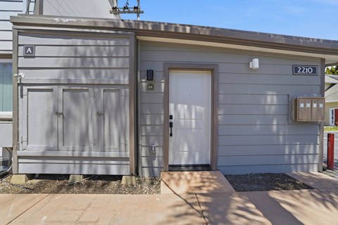 A grey building with a white door and a sign that reads 2210.
