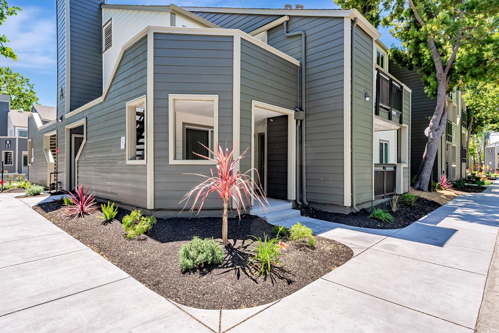 A modern house with a grey exterior and a small garden in front.