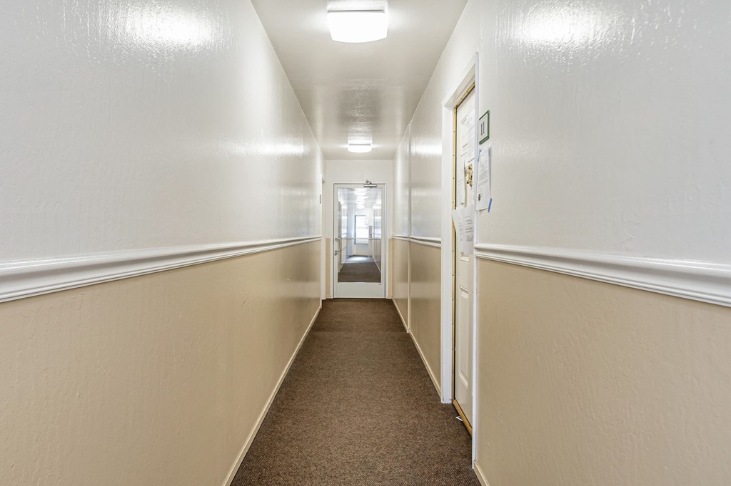 A hallway with white walls and carpeted floor.