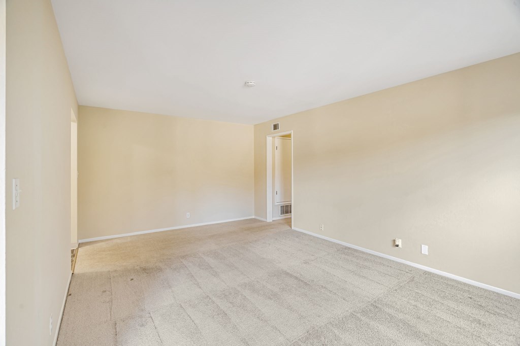 Empty room with carpeted floor and white walls.
