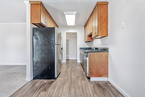 A kitchen with a black refrigerator and wooden cabinets.