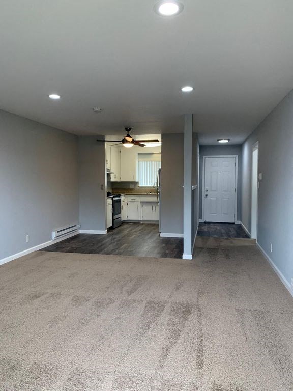 A room with a carpeted floor and a ceiling fan.