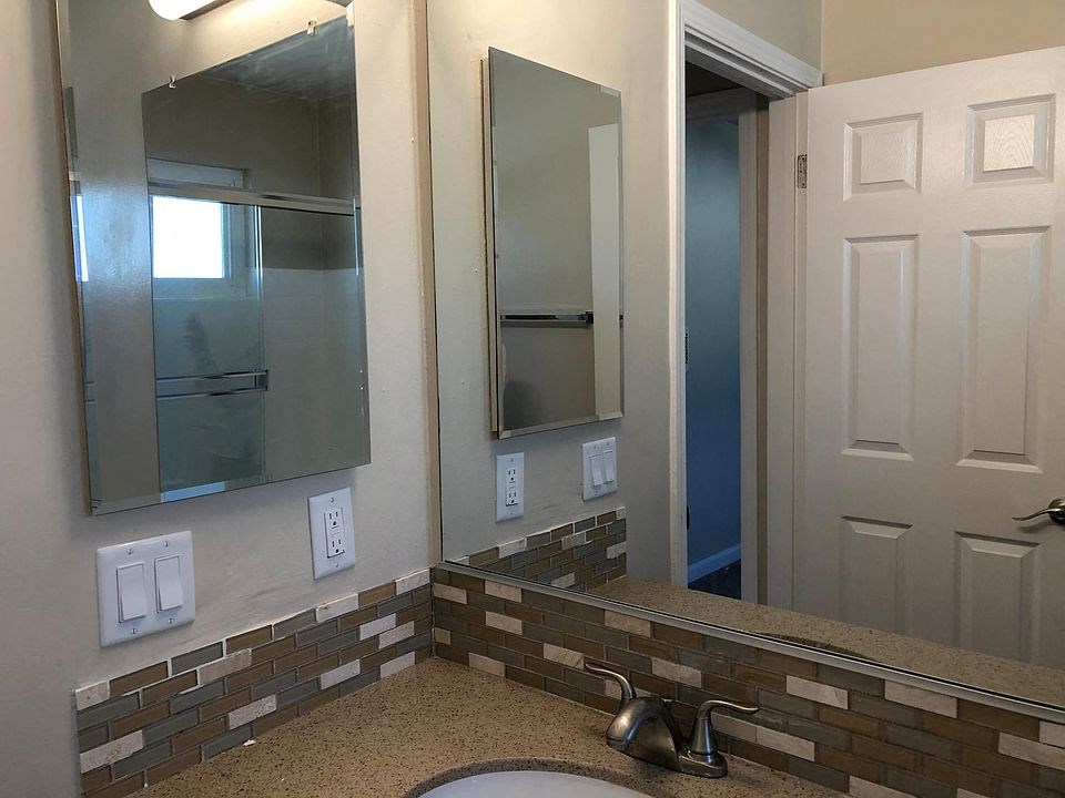 a bathroom with a sink and two mirrors