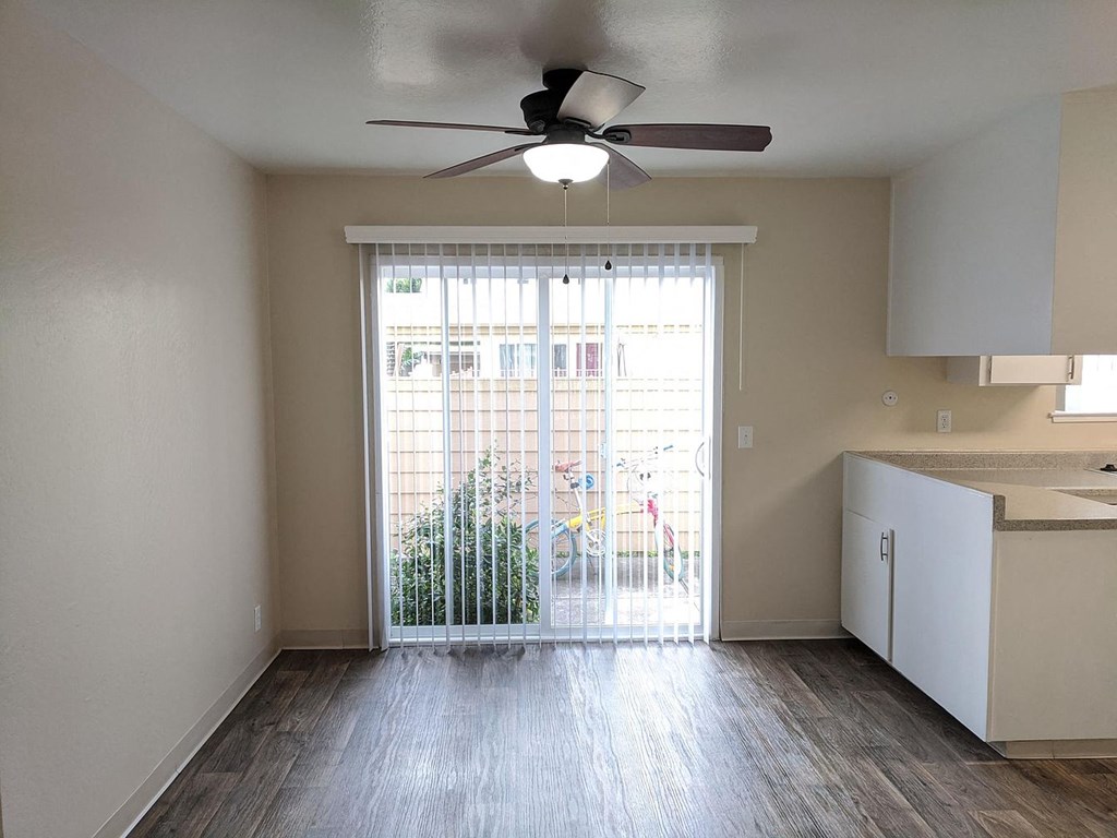 an empty living room with a large window and a ceiling fan