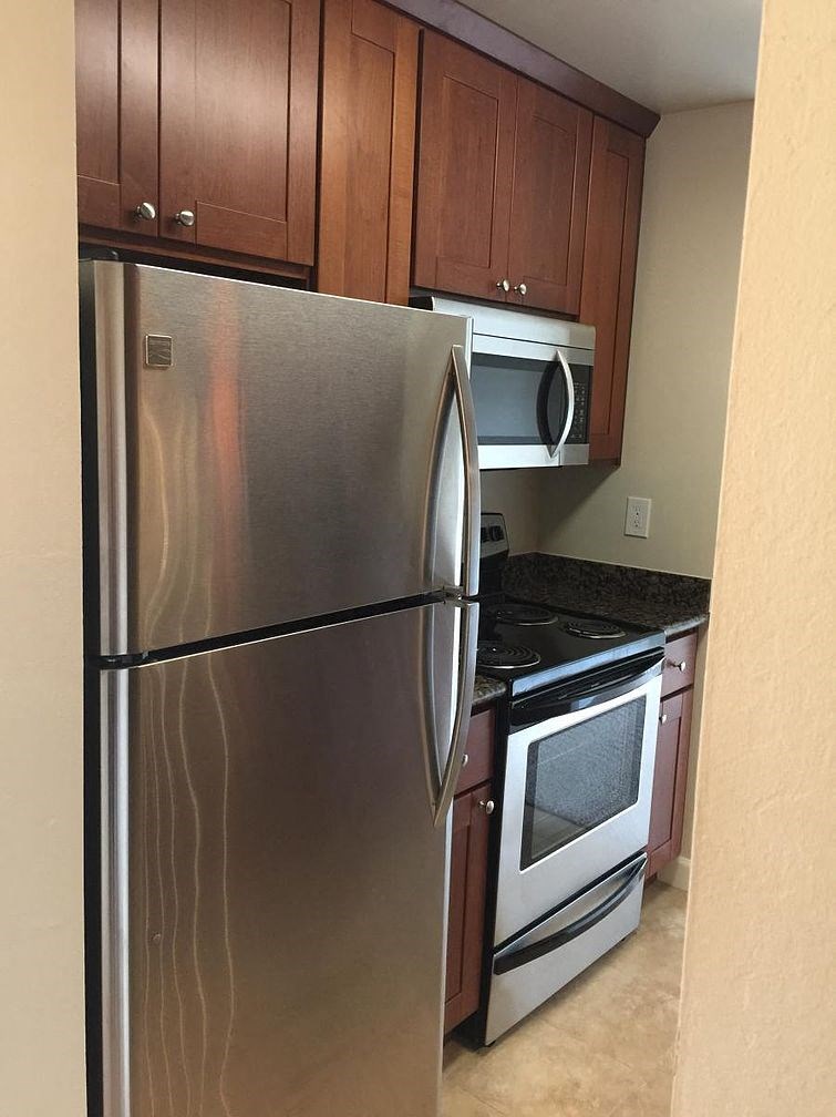 A stainless steel refrigerator with a black oven beneath it.
