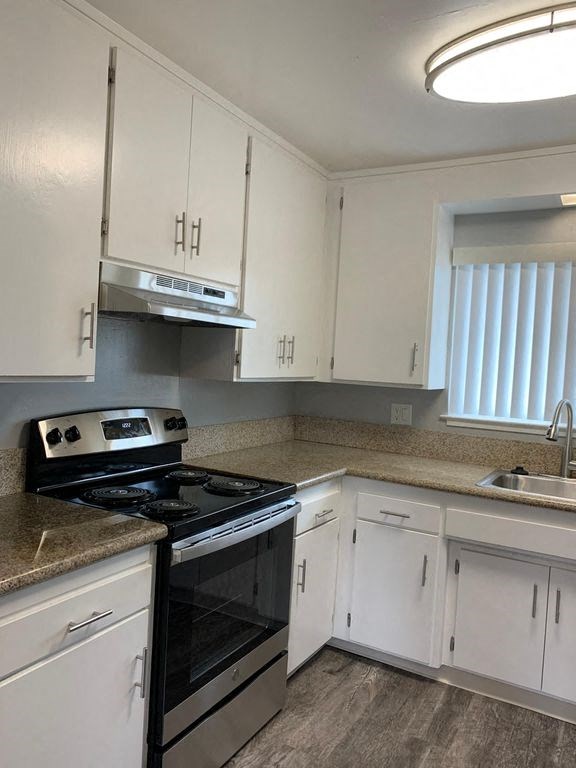 A kitchen with white cabinets and a black stove top oven.