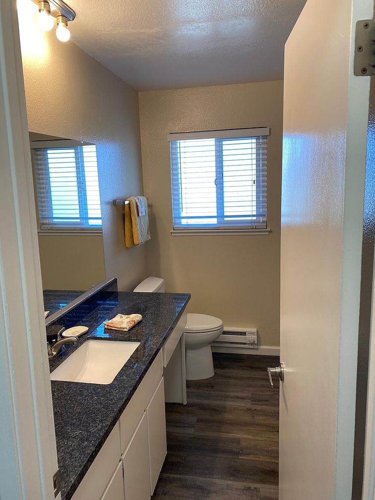 A bathroom with a toilet, sink, and window.