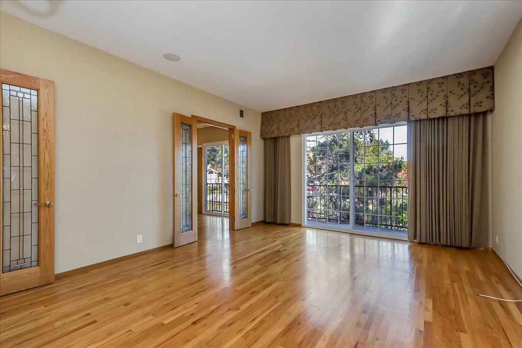an empty living room with wood floors and a large window
