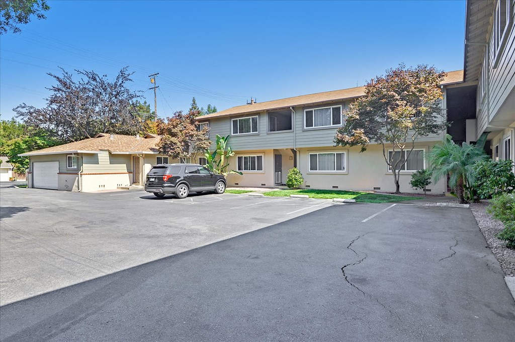 A car is parked in a parking lot in front of a building.