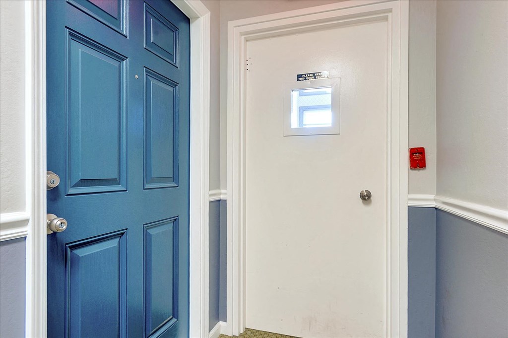 a blue door in a room with a white wall and a door with a window