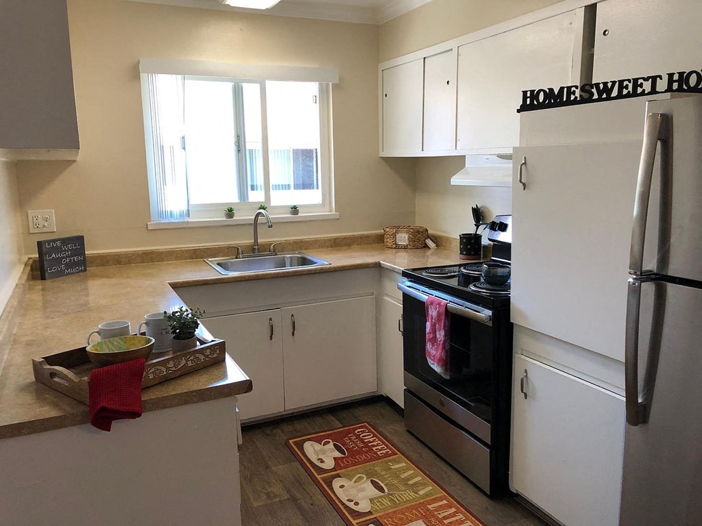 A kitchen with a refrigerator, sink, and oven.