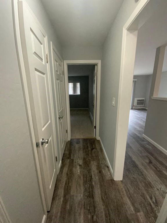 A hallway with white doors and wood flooring.