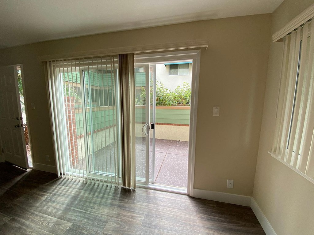 an empty living room with large windows and a ceiling fan