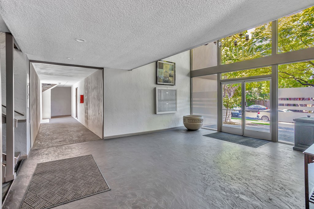 A hallway with a rug on the floor and a wall with a mirror on the side.