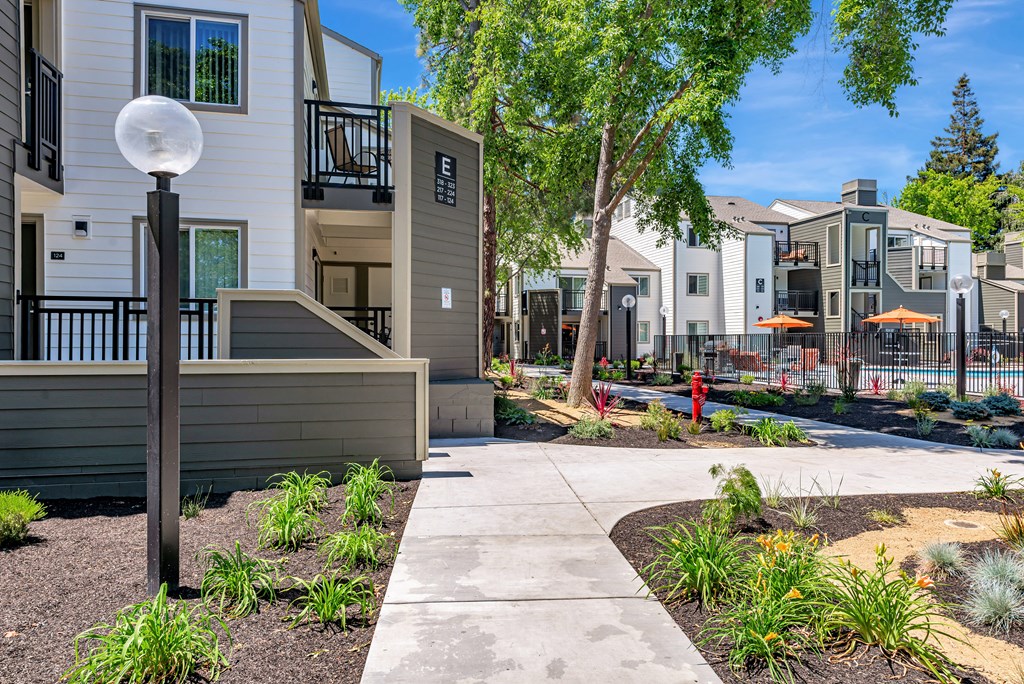 A modern apartment complex with a well-maintained garden in the foreground.