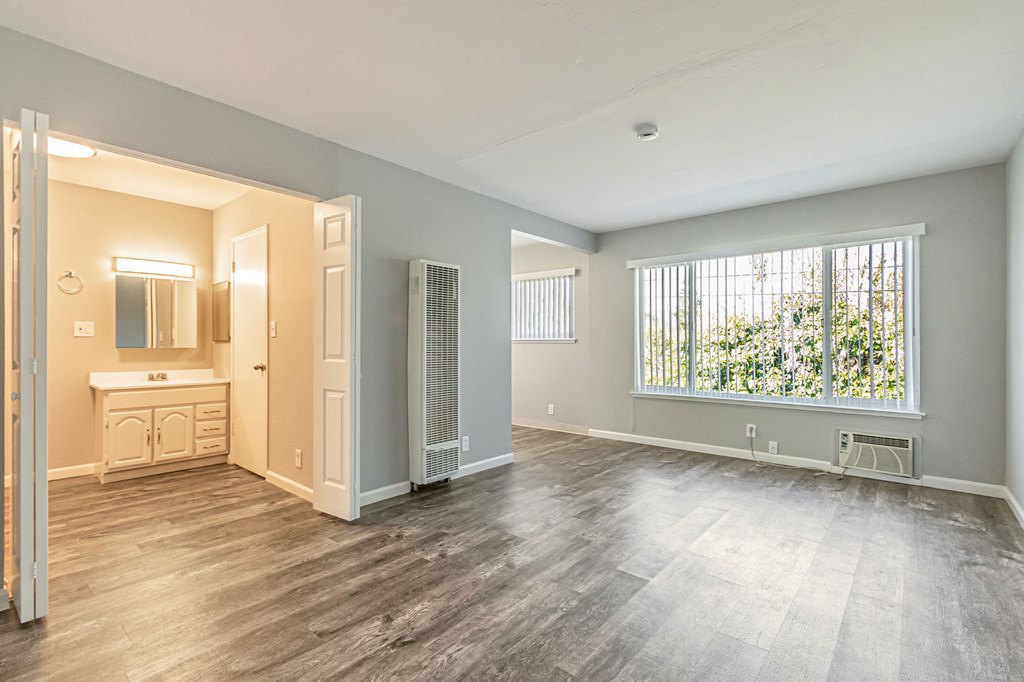 A large empty room with a window overlooking trees.