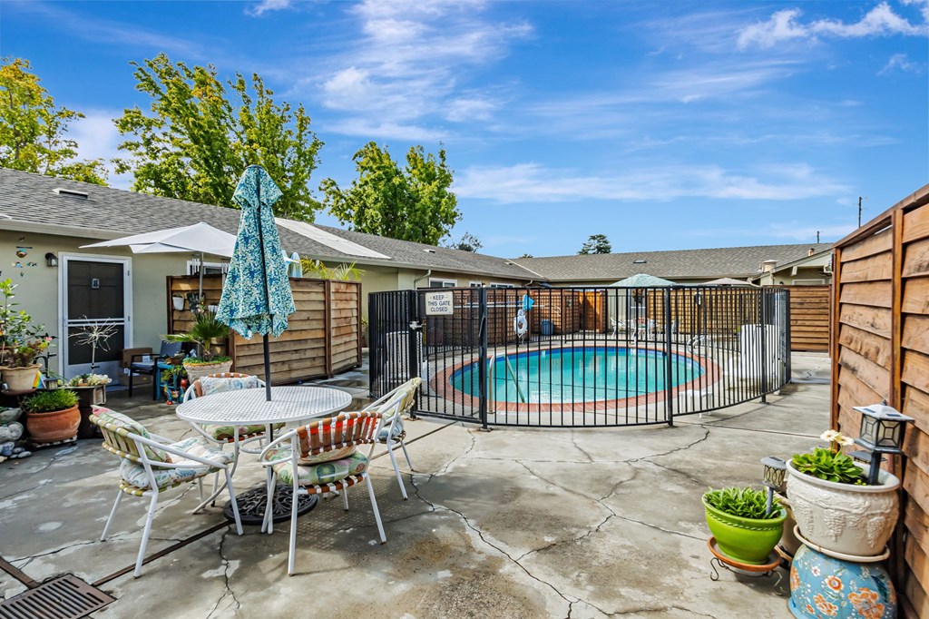 A patio with a table, chairs, and a pool.