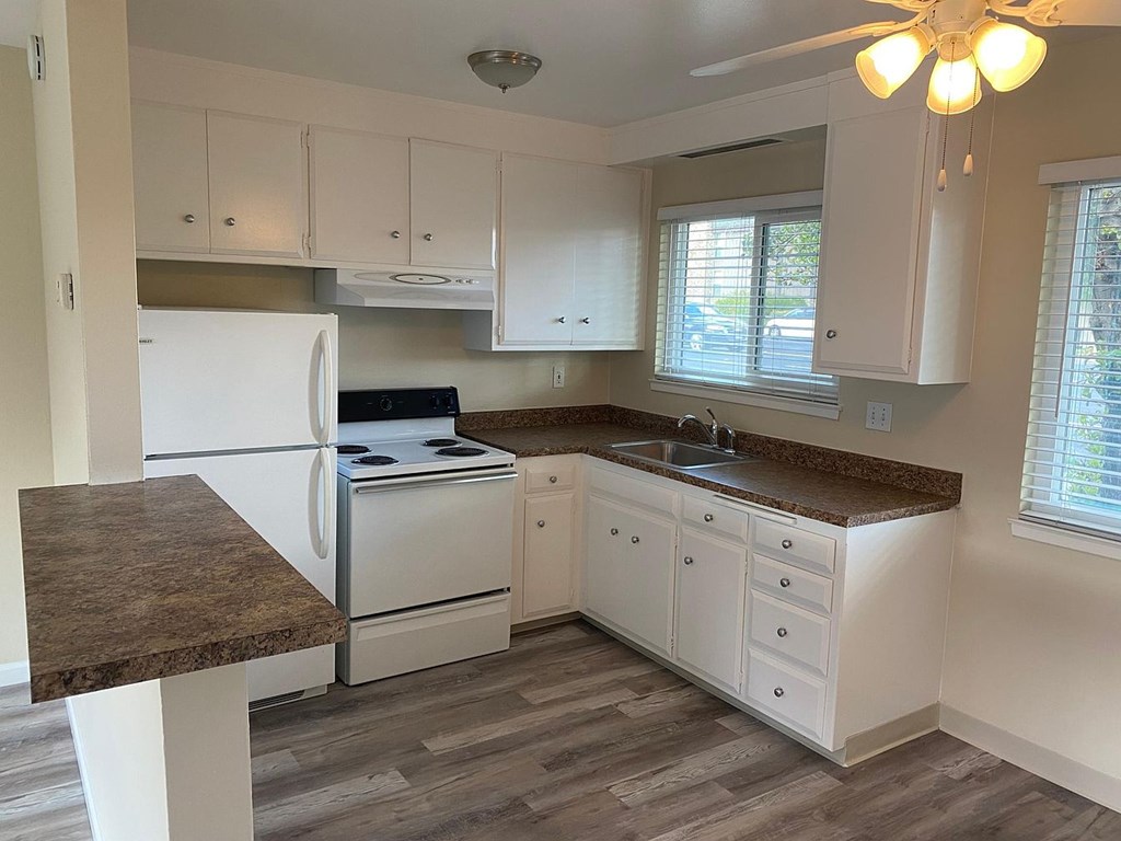 A kitchen with white cabinets and a marble countertop.