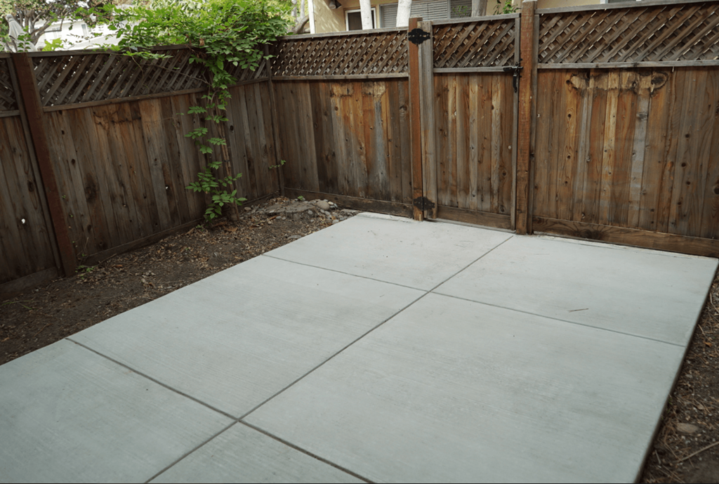 a stamped concrete patio in front of a wooden fence