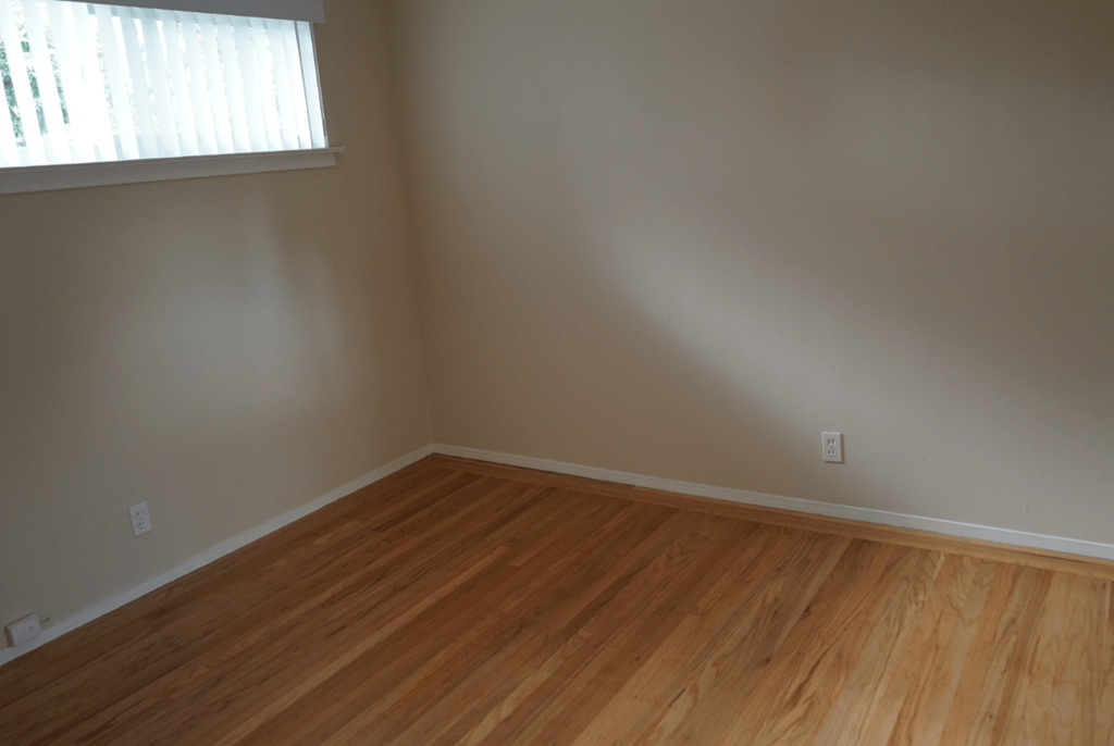 an empty room with wooden floors and a window