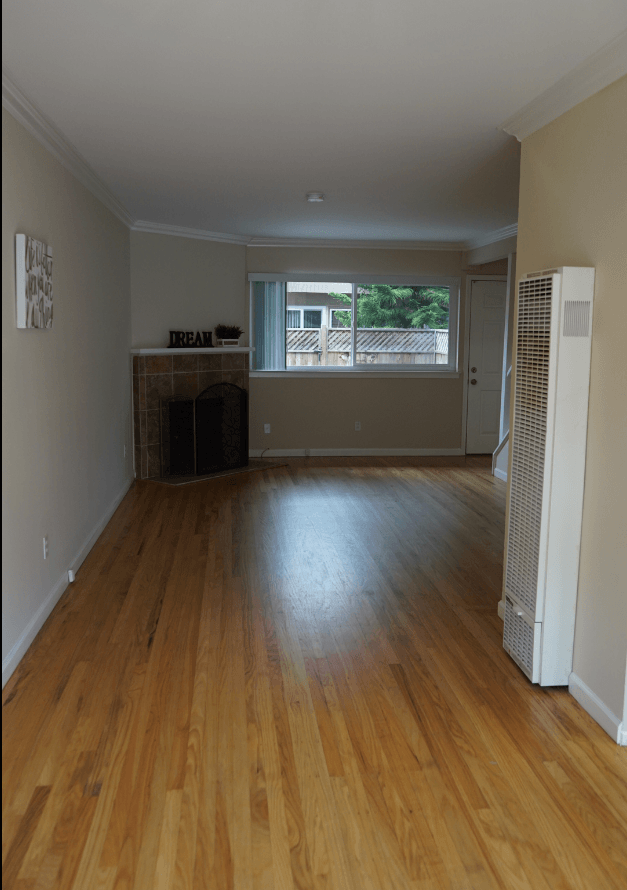 an empty living room with wood floors and a fireplace