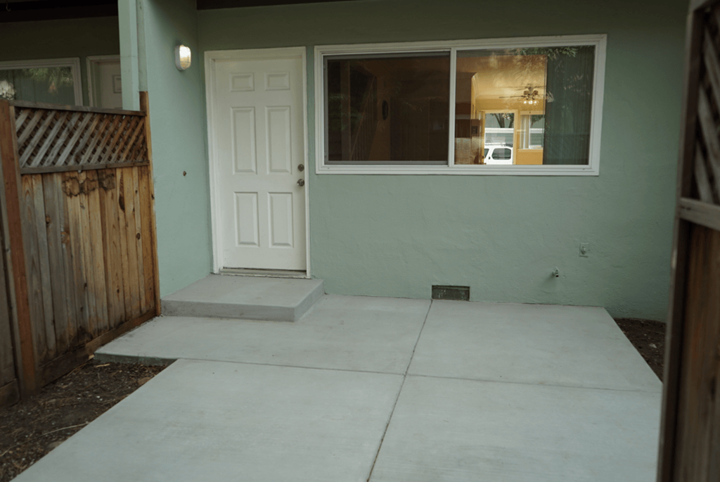 the front entrance of a house with a concrete walkway and a white door