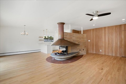 A modern living room with a wood stove in the center.