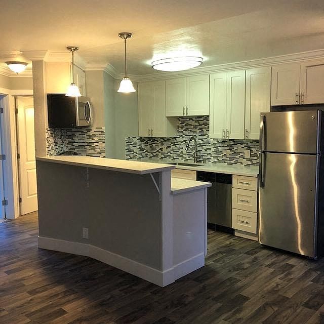 A kitchen with a white island and a stainless steel refrigerator.