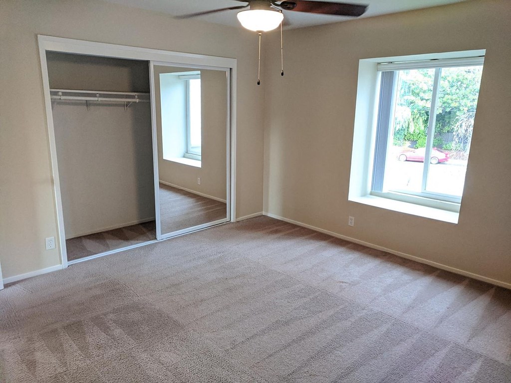 an empty living room with a closet and a window