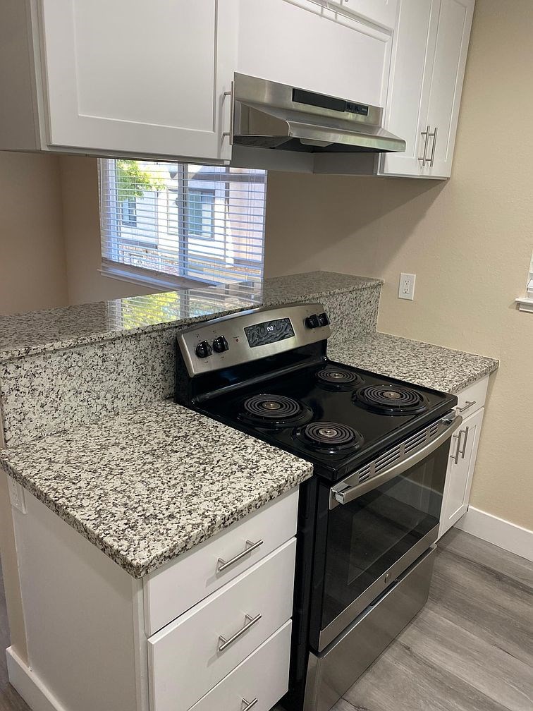 A kitchen with granite countertops and white cabinets.