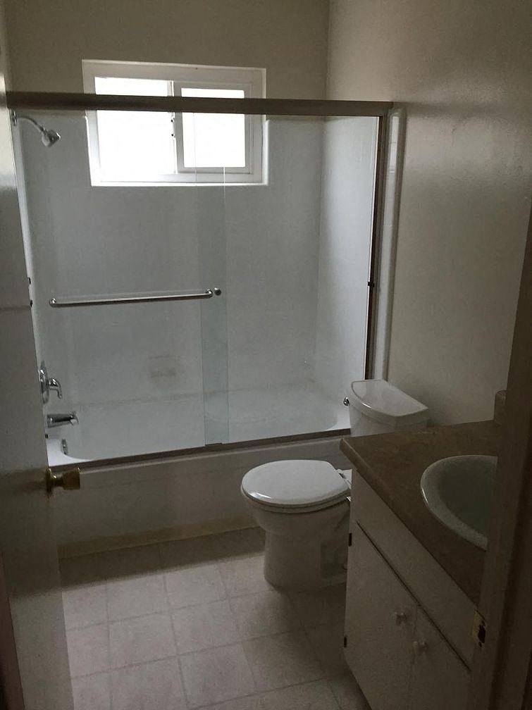 A white toilet sits in a bathroom next to a sink.