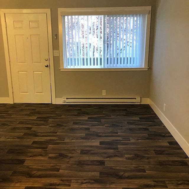 A room with a wooden floor and a window with blinds.