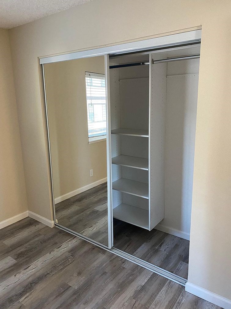 A large white closet with shelves and a mirror.