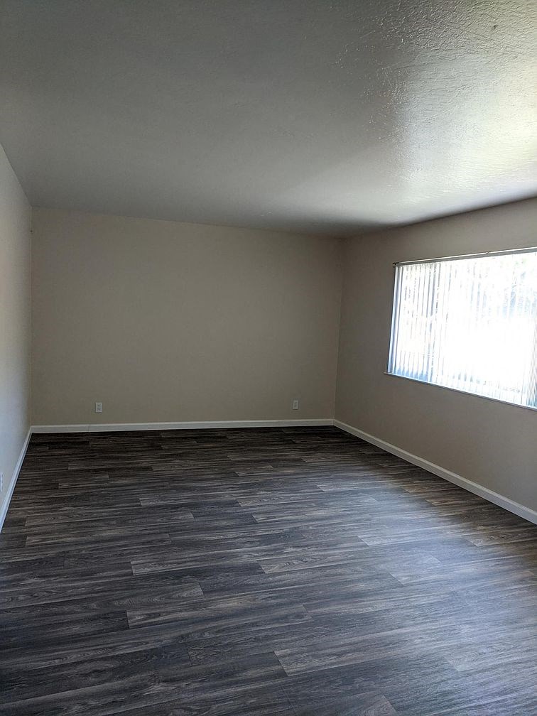 A room with wooden flooring and a window letting in sunlight.