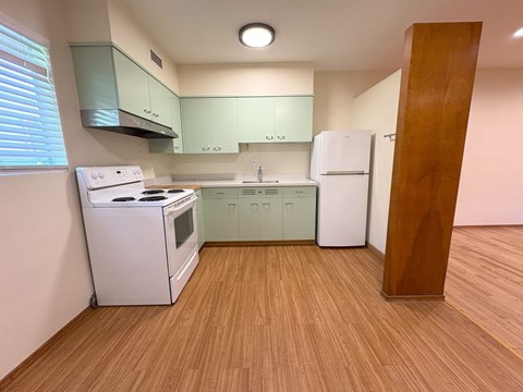 A kitchen with a white stove and green cabinets.