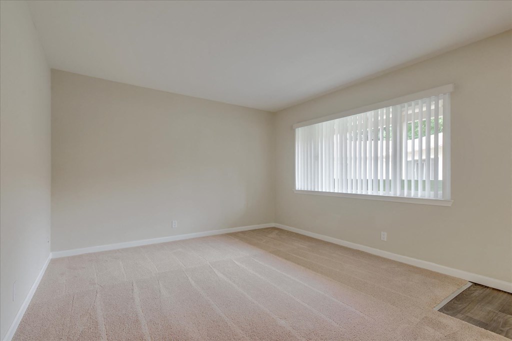 an empty living room with a large window and tiled floors