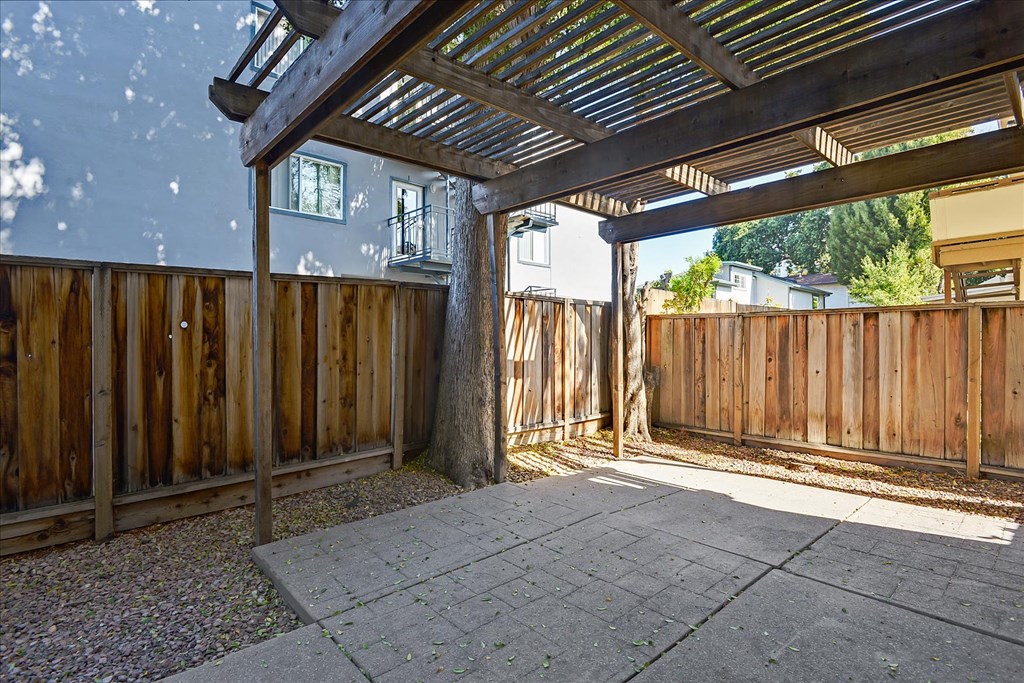 a backyard with a wooden fence and a patio with a pergola