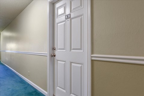 a white door in a room with white walls and a blue carpet