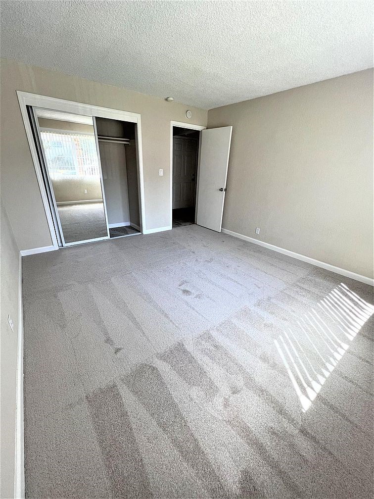 A room with a carpeted floor and two doors.