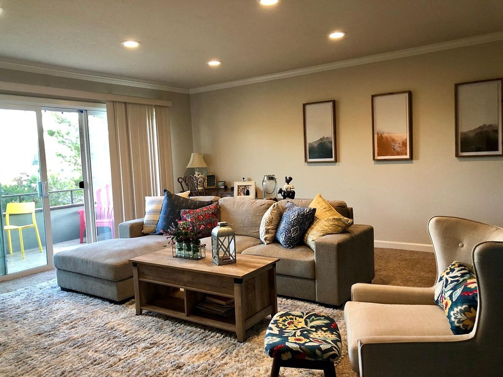 A living room with a grey couch, a wooden coffee table, and a chair with a floral pattern.