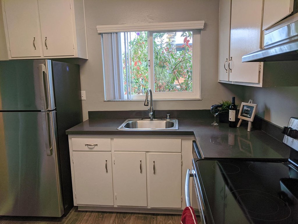 A kitchen with white cabinets and a black countertop.