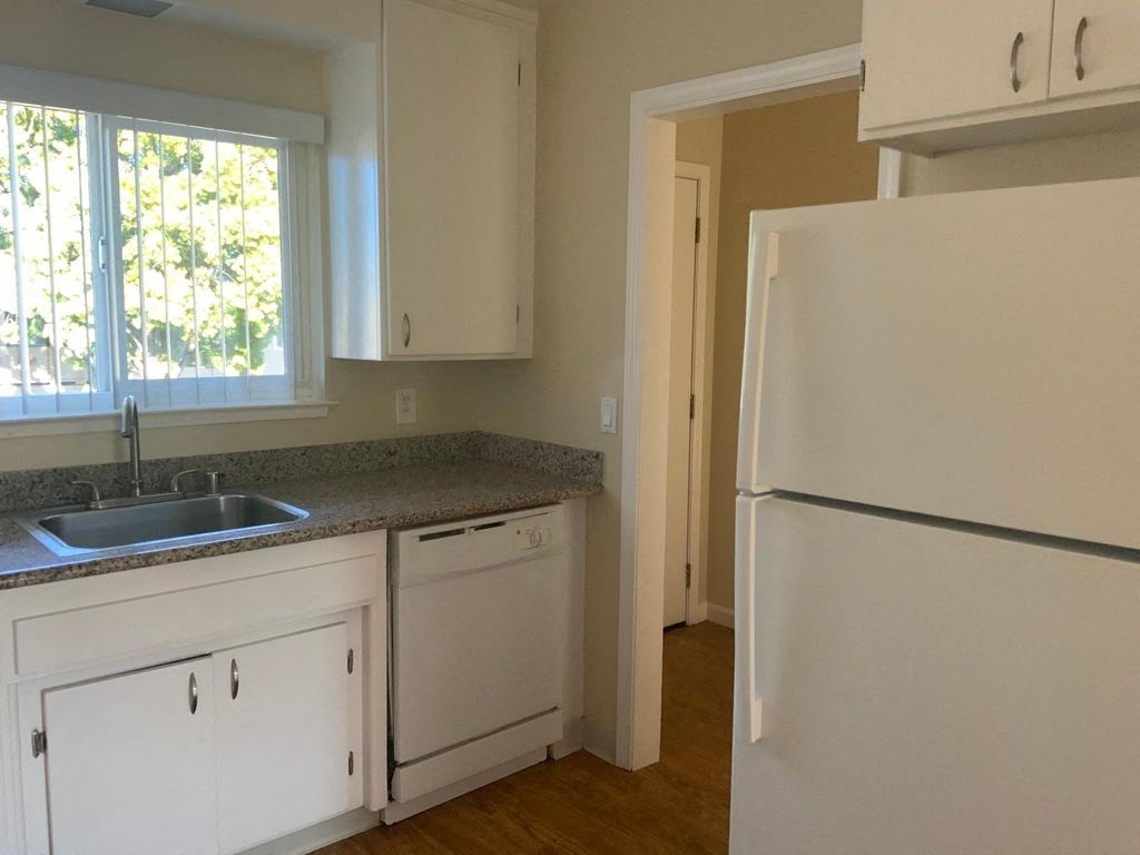 A kitchen with white cabinets and a white refrigerator.