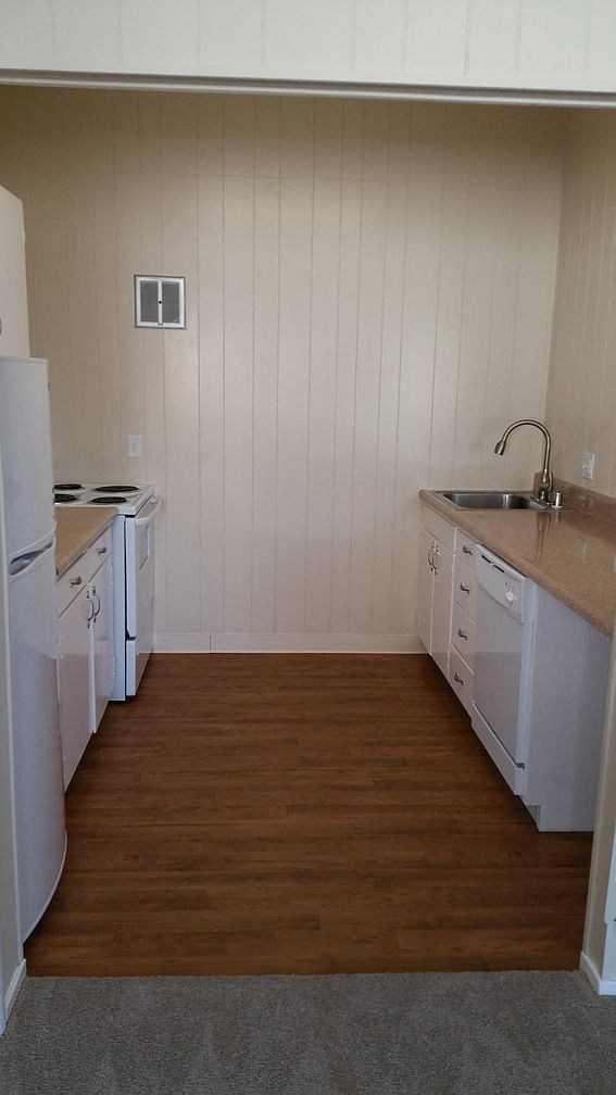 A kitchen with white appliances and wooden floors.