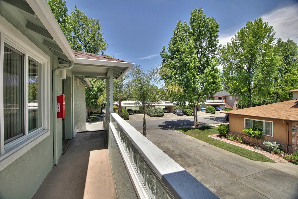the view from the balcony of a building with trees and a sidewalk