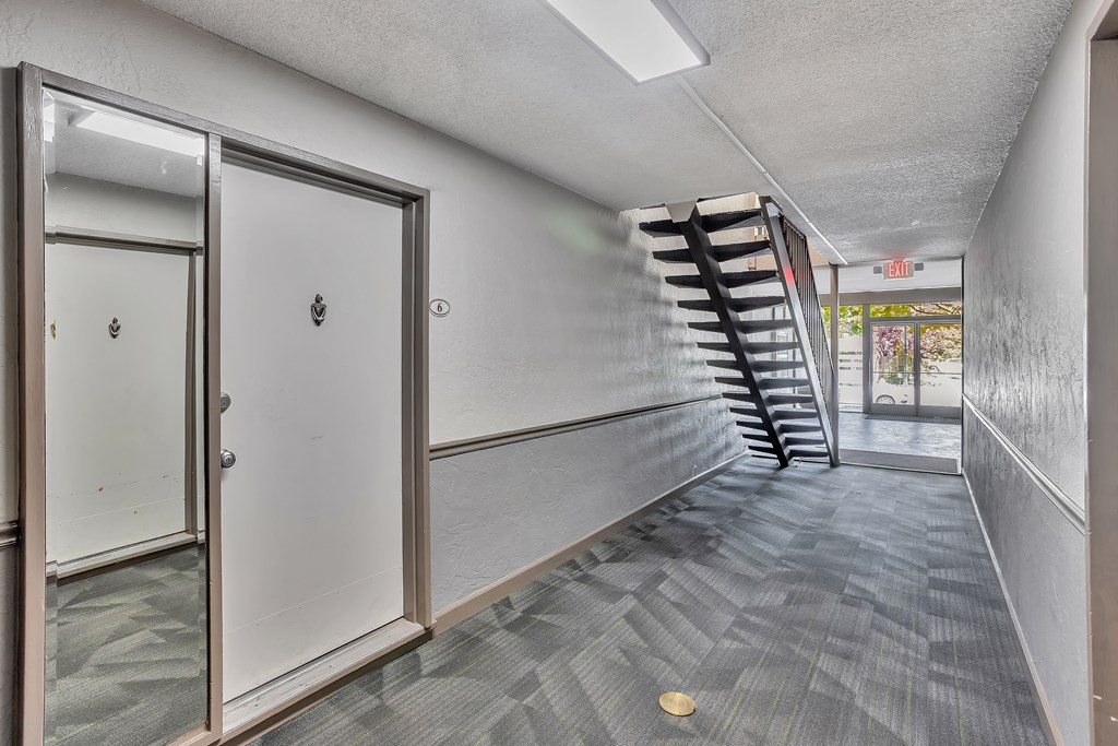 A hallway with a staircase on the right and a door on the left.