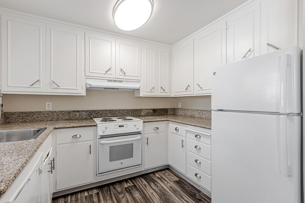 A white kitchen with a refrigerator on the right.