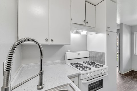A white kitchen with a stove and a hose.